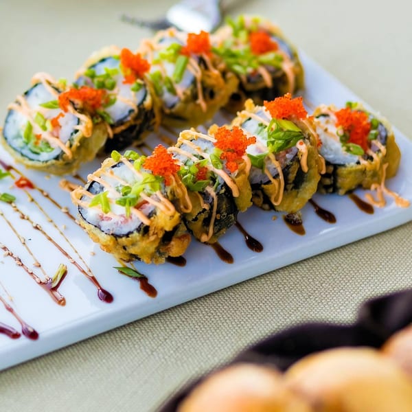 My Sushi & Catering LLC's fried sushi rolls with orange roe, green onions, and sauce drizzle.