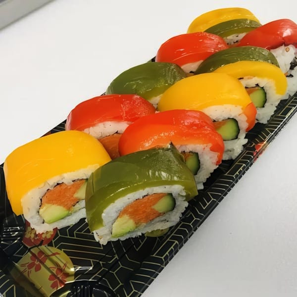 Colorful sushi rolls with red, yellow, and green toppings, arranged on a black patterned tray.